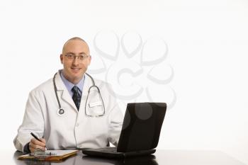 Royalty Free Photo of a Physician Sitting at a Desk With a Laptop Computer