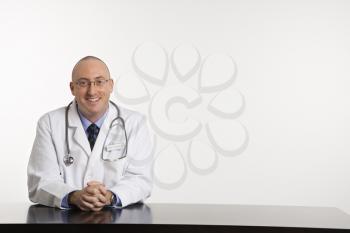 Royalty Free Photo of a Male Physician Sitting at a Desk Smiling