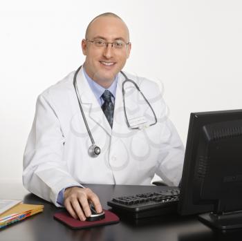 Royalty Free Photo of a Male Physician Sitting at a Desk With a Laptop
