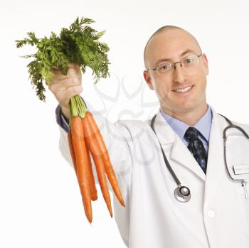 Royalty Free Photo of a Male Physician Holding a Bunch of Carrots