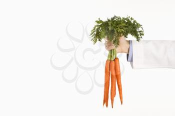 Caucasian mid adult male physician holding bunch of carrots.