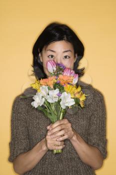 Royalty Free Photo of a Pretty Asian Woman Holding a Bouquet of Flowers Up to Her Face
