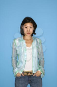 Half length portrait of pretty Asian mid adult woman  on blue background.