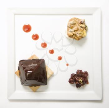 Royalty Free Photo of Chocolate Cheesecake Pyramid With Dried Cherries and Pistachio Praline