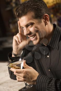 Royalty Free Photo of a Man Holding a Martini With Hand to Head and Smiling