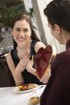 Royalty Free Photo of a Man Giving a Heart Shaped Box of Chocolates to a Woman at a Restaurant