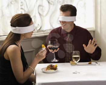 Royalty Free Photo of a Couple Dining in a Restaurant With Blindfolds Over Their Eyes