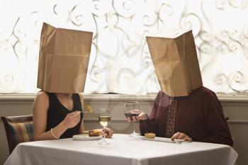 Royalty Free Photo of a Couple Dining in a Restaurant With Paper Bags Over Their Heads