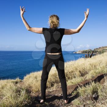 Royalty Free Photo of a Woman Standing on Maui, Hawaii Coast With Her Arms Raised Above Her Head