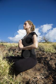Royalty Free Photo of a Woman Sitting in Yoga Lotus Position on Rocks in Maui, Hawaii