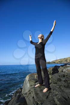 Royalty Free Photo of a Woman Standing on the Rocky Coast of Maui, Hawaii With Arms Outstretched