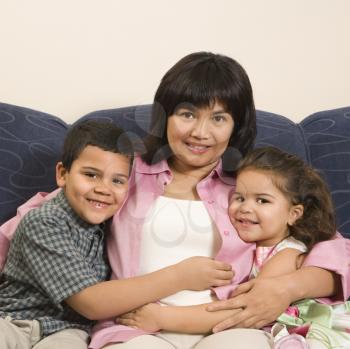 Royalty Free Photo of a Family Sitting on a Couch Hugging and Smiling