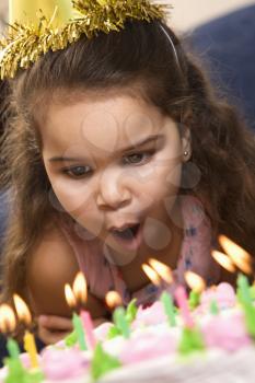 Royalty Free Photo of a Girl Wearing a Party Hat Blowing Out Candles on a Birthday Cake
