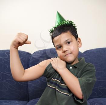 Royalty Free Photo of a Boy Wearing a Party Hat and Playfully Flexing His Arm Muscle 