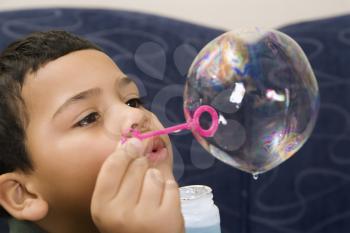 Royalty Free Photo of a Boy Blowing Large Soap Bubble