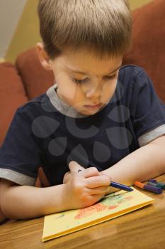Royalty Free Photo of a Boy Drawing With Crayons