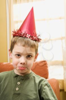 Royalty Free Photo of a Boy Wearing a Party Hat Pouting