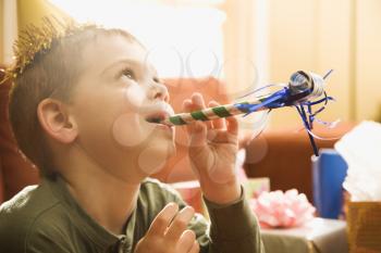 Royalty Free Photo of a Boy at a Birthday Party Blowing Noisemaker