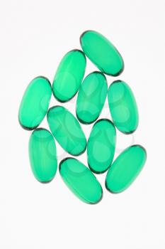 Green capsule pills against white background.