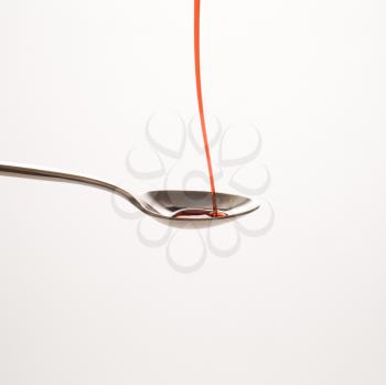 Royalty Free Photo of Red Cough Syrup Being Poured on a Spoon