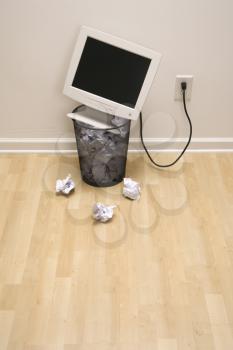 Royalty Free Photo of a Computer Monitor in a Trash Can Surrounded by Crumpled Up Paper