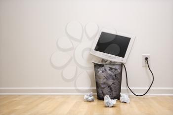 Royalty Free Photo of a Computer Monitor in a Trash Can Surrounded by Crumpled Up Paper