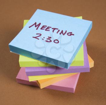 Royalty Free Photo of a Stack of sticky notes with a meeting reminder