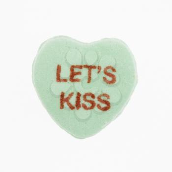 Royalty Free Photo of a Green Candy Heart That Reads Let's Kiss 