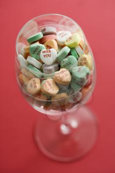 Royalty Free Photo of a Wine Glass Full of Colorful Candy Hearts With Sayings on Them