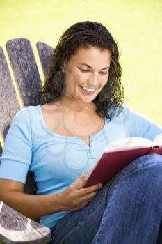 Royalty Free Photo of a Smiling Woman Sitting in a Chair Reading a Book