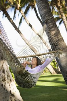 Royalty Free Photo of a Pretty Young Female Lying in a Hammock With Arms Behind Her Head Resting With Eyes Closed