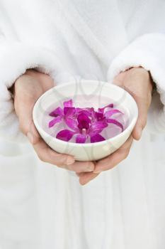Royalty Free Photo of a Woman's Hands Holding a Bowl with Purple Orchids Floating in Water