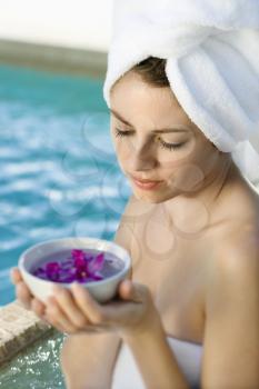 Royalty Free Photo of a Woman Wearing a Towel Around Her Head and Holding a Bowl of Purple Orchids