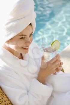 Royalty Free Photo of a Woman Wearing a Robe Drinking Next to a Pool