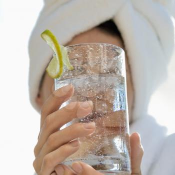 Royalty Free Photo of a Woman With a Towel on Her Head Holding a Drink in Front of Her Face