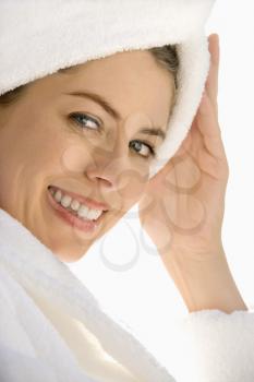 Caucasian mid-adult woman wearing towel around head with hand on head smiling at viewer.