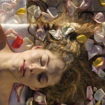Royalty Free Photo of a Woman Lying Down With Rose Petals in Her Hair