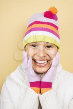 Royalty Free Photo of a Woman Wearing Winter Hats and Gloves With Hands to Face Smiling