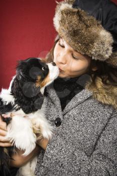 Royalty Free Photo of a Young Woman Wearing a Fur Hat Kissing a King Charles Spaniel