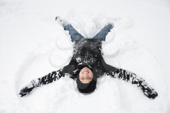 Royalty Free Photo of a Woman Lying in the Snow Making a Snow Angel