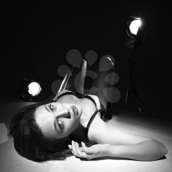 Royalty Free Photo of a Sexy Woman in Lingerie Lying on the Floor With Spotlights Looking Up