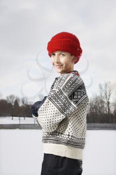 Royalty Free Photo of a Boy Wearing a Sweater and Red Winter Cap Looking Over Shoulder and Smiling