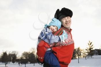 Royalty Free Photo of a Man Giving His Daughter a Piggyback