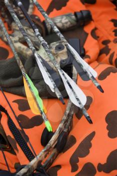 Royalty Free Photo of a Still life shot of bow and arrows laying against blaze orange camouflage.