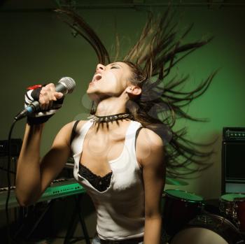 Royalty Free Photo of a Female Swinging Her Head and Hair While Singing Into a Microphone