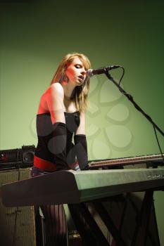 Royalty Free Photo of a Woman Singing into a Microphone and Playing Keyboard