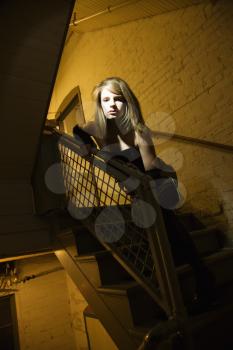 Royalty Free Photo of a Female Posing in a Stairwell With Direct Light on Her Face