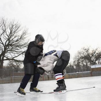 Royalty Free Photo of Ice Hockey Player Boy Roughing Up Another Player on the Ice Rink