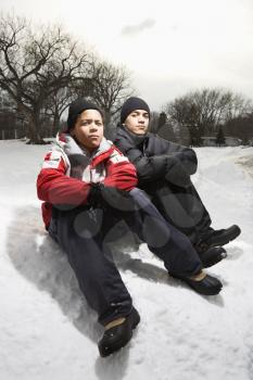 Royalty Free Photo of Two Boys Sitting in Snow Wearing Coats and Hats