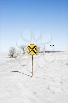 Royalty Free Photo of a Railroad Crossing Sign in as Snow Covered Rural Landscape